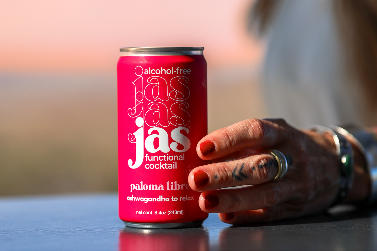 Holding a can of JAS Paloma Libre at sunset