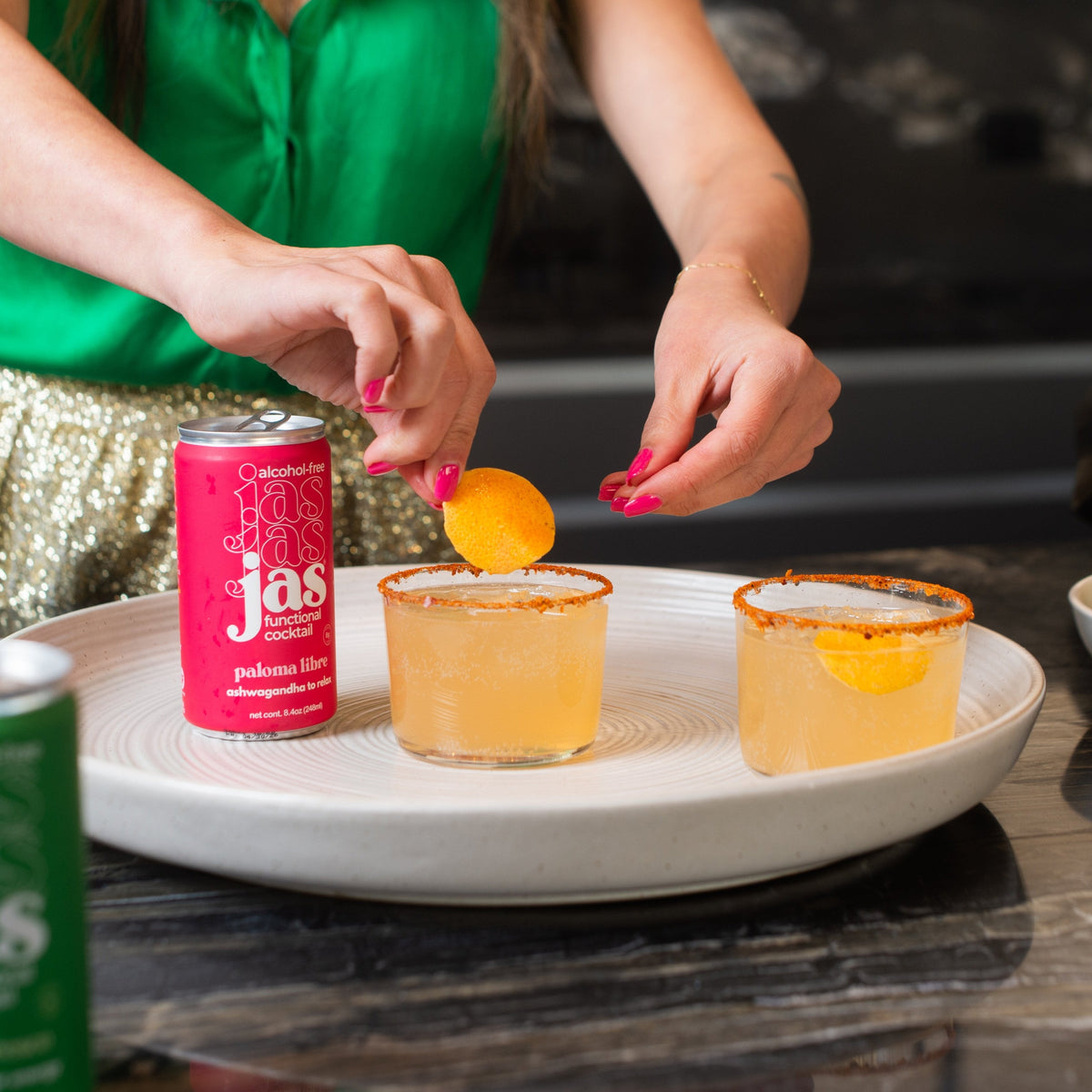 A non-alcoholic Paloma in a glass with a grapefruit garnish and a can of JAS Paloma Libre